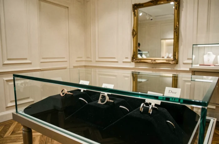 Vitrine de bijouterie Dior présentant des bagues en or rose, or blanc et titane sur velours noir dans une boutique parisienne élégante